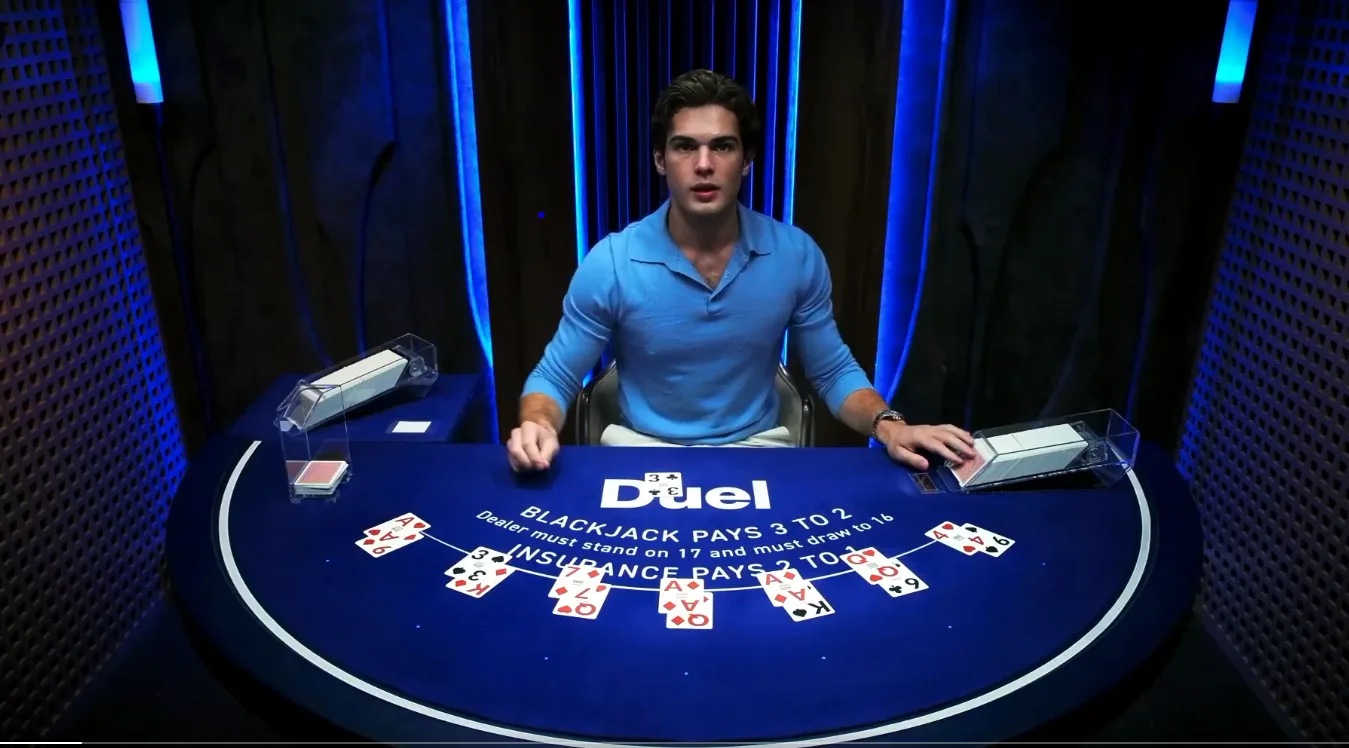 Duel live blackjack table showing the dealer, the rules printed on the felt and a dealt hand